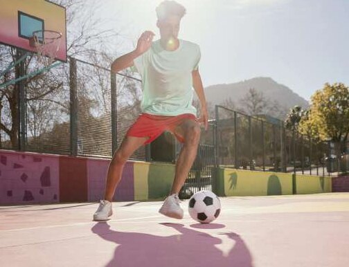 Joven controlando un balón de fútbol en una cancha al aire libre