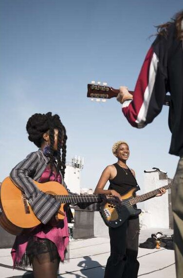 Músicas tocando guitarra y bajo al aire libre